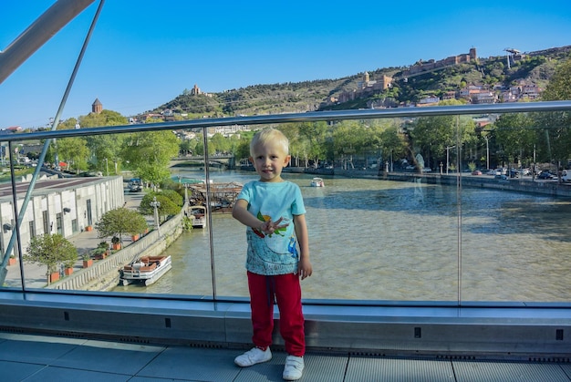 Petit garçon sur le fond de la rivière Kura depuis le pont par une claire journée ensoleillée Rivière Kura dans le centre de Tbilissi 27 avril 2019 Tbilissi Géorgie