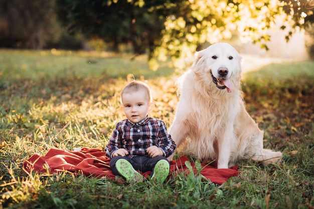 Petit garçon et un golden retriever assis dans un magnifique parc d'automne