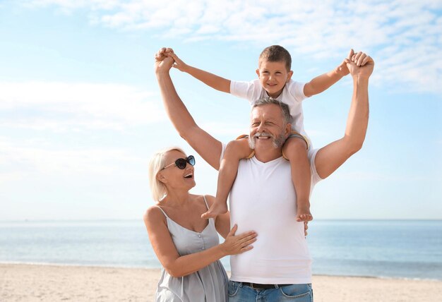 Petit garçon et heureux grands-parents passent du temps ensemble sur la plage de la mer