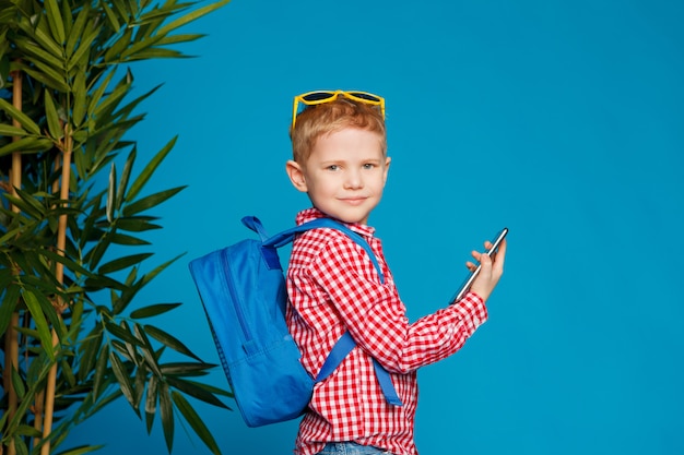 Petit Garçon Hipster Avec Sac à Dos Et Lunettes De Soleil Tenant Un Téléphone