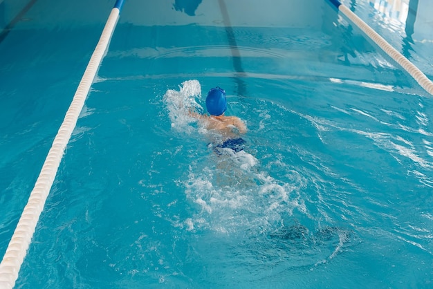 Un petit garçon de huit ans apprend à nager dans une piscine moderne Développement des sports pour enfants Parentalité saine et promotion des sports pour enfants