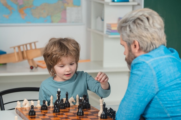 Petit garçon intelligent pensant aux échecs Succès et victoire aux échecs Retour à l'école Joli garçon développant une stratégie d'échecs Joli petit garçon jouant aux échecs avec son père