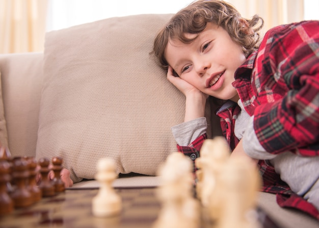 Petit garçon intelligent sourit en jouant aux échecs.