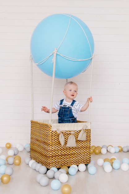 Petit garçon en jeans sur un ballon bleu sur fond blanc.