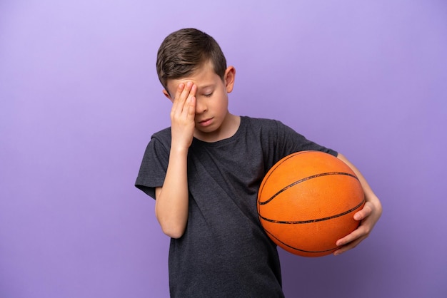 Petit garçon jouant au basket-ball isolé sur fond violet avec mal de tête