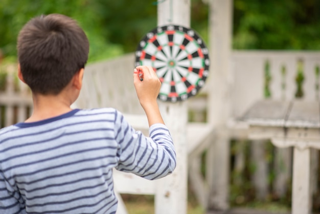 Petit garçon jouant au jeu de fléchettes en famille