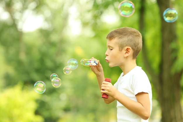 Petit garçon jouant avec des bulles dans le parc