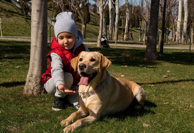 Petit garçon jouant avec un chien labrador dans le parc du printemps