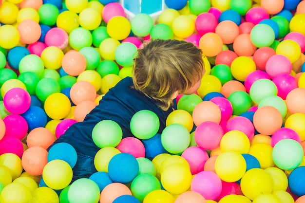 Petit garçon jouant dans la piscine de boules en plastique colorées