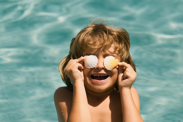 Petit garçon jouant dans une piscine extérieure dans l'eau bleue pendant les vacances d'été sur la plage tropicale