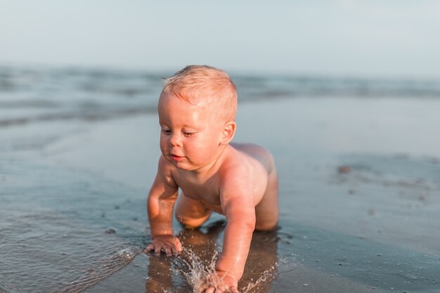 Petit garçon jouant avec du sable au bord de la mer