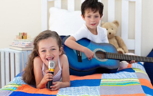 Petit garçon jouant de la guitare et sa soeur chantant