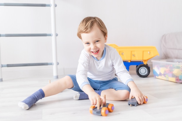 Petit garçon jouant avec des jouets en bois à la maison sur le sol