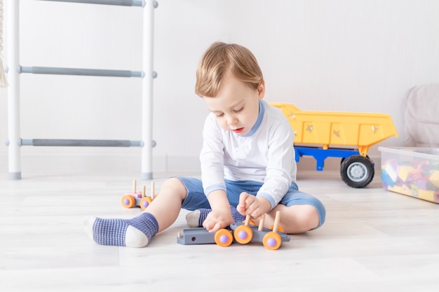 Petit garçon jouant avec des jouets en bois à la maison sur le sol