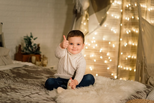 Petit garçon jouant avec des jouets à la maison près de la cheminée et de l'arbre de Noël.