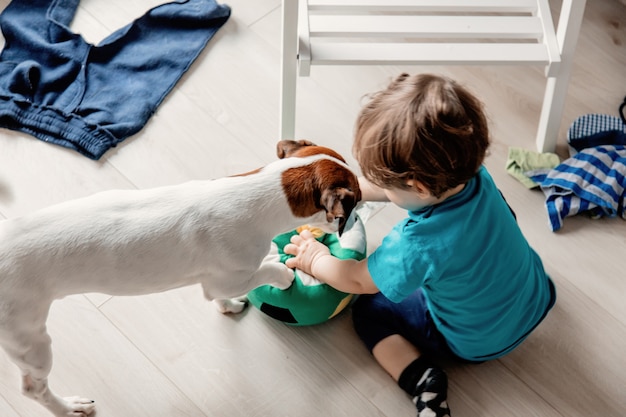 Petit garçon jouant à la maison avec son chien Jack Russell Terrier.