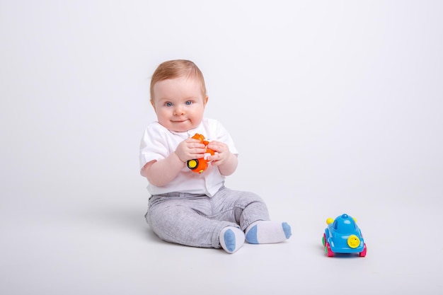 Petit garçon jouant avec des petites voitures sur fond blanc