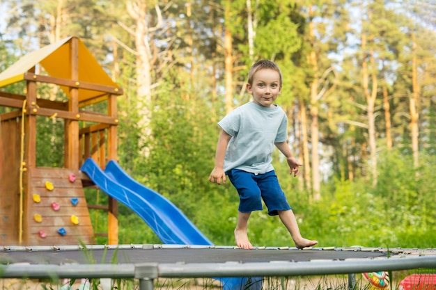 Petit garçon jouant sur le terrain en sautant sur un trampoline sur la pelouse