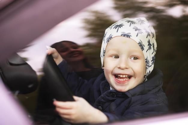 Petit garçon jouant avec un volant dans une voiture. Mains d'un petit enfant conduisant une voiture. enseignement de la conduite dans l'enfance.