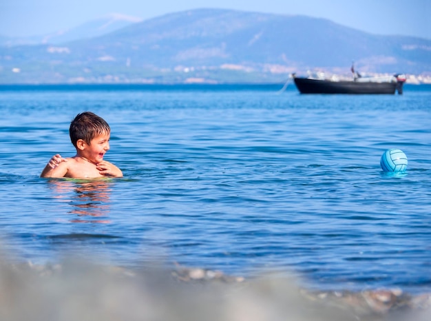 Un petit garçon joue au ballon dans la mer Égée sur une île grecque