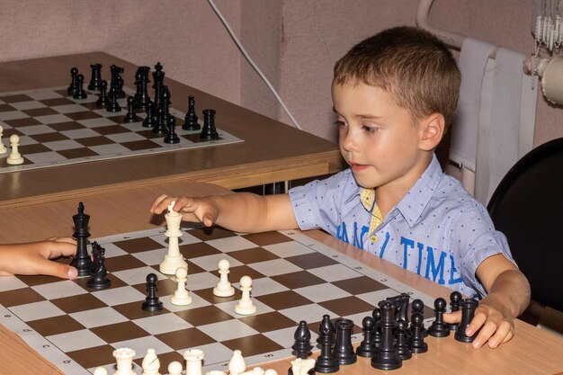 Photo un petit garçon joue aux échecs avec un adversaire