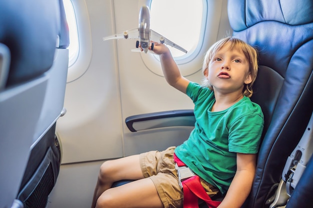 Petit garçon joue avec un avion jouet dans l'avion à réaction commercial volant en vacances