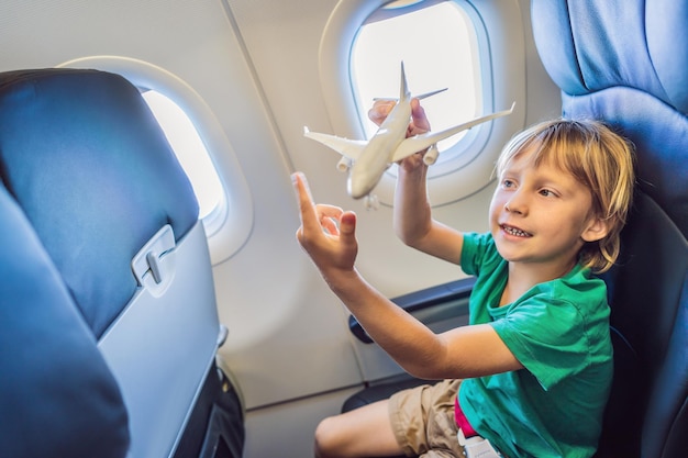 Petit garçon joue avec un avion jouet dans l'avion à réaction commercial volant en vacances