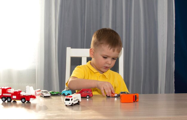 Un petit garçon joue avec des petites voitures à la maison. Ses voitures sont sa chose préférée pour jouer avec.