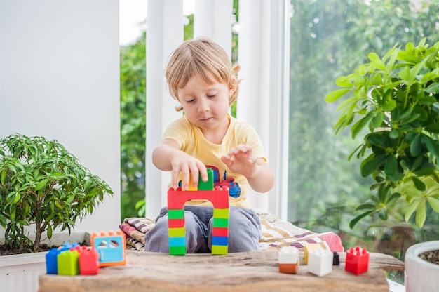 petit garçon avec jouer avec des blocs de plastique colorés à l'intérieur