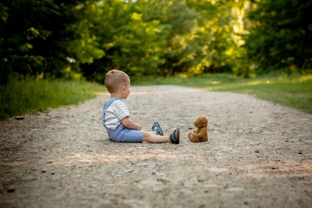 Petit garçon, jouer, à, ours peluche, sur, les, sentier