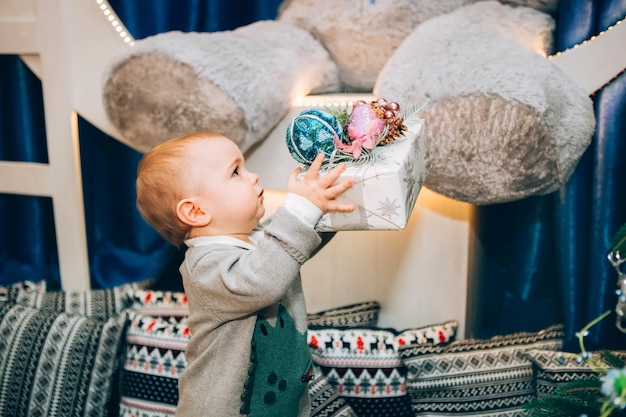 Petit garçon avec jouet près de décor de Noël et arbre de Noël