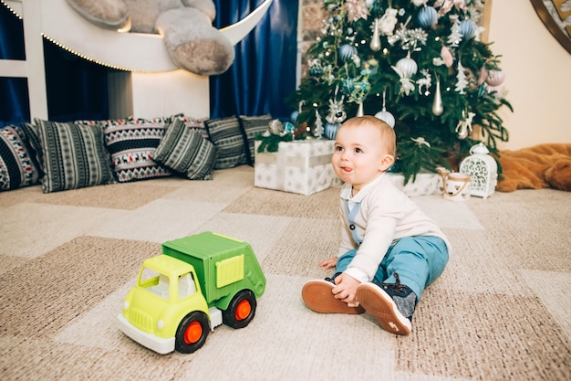 Petit garçon avec jouet près de décor de Noël et arbre de Noël