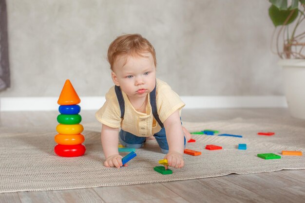 Petit garçon avec des jouets rampant sur le sol à la maison