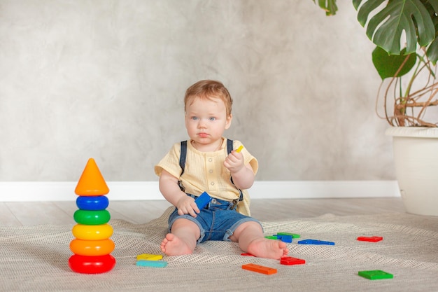 Petit garçon avec des jouets rampant sur le sol à la maison