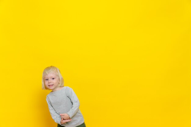 Un petit garçon joyeux regarde avec un sourire.