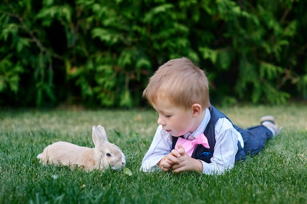 Petit garçon avec un lapin couché sur l&#39;herbe