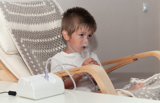 Petit garçon malade avec masque nébuliseur faisant l'inhalation