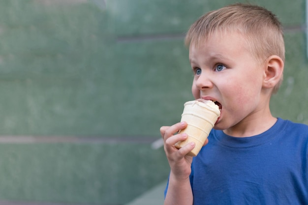 Un petit garçon mange de la glace L'enfant est emporté en mangeant de la glace citronchocolat dans une tasse à gaufres Délicatesse pour bébé