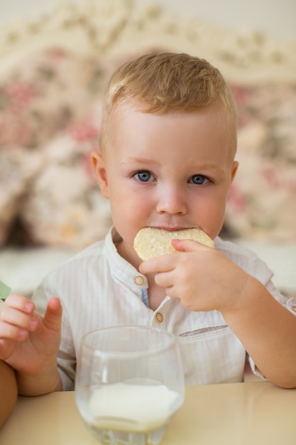 Petit garçon mangeant des biscuits avec du lait à la maison