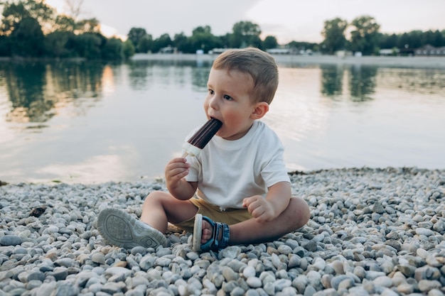petit garçon mangeant de la glace lors d'une promenade sur le lac