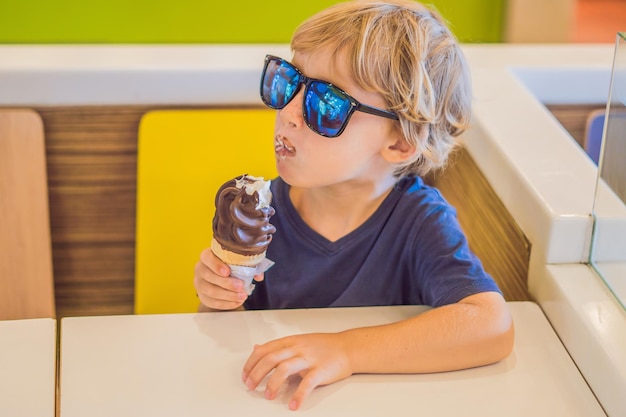 Petit garçon mangeant des glaces dans un café.