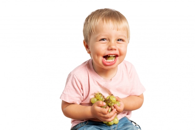 Petit garçon mangeant des raisins et souriant