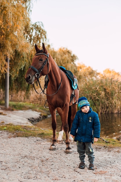 Petit garçon marchant à cheval dans le parc d'automne
