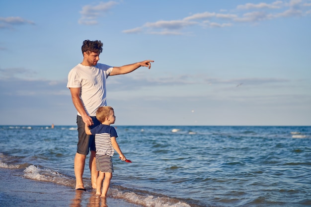 Petit garçon marchant avec le père à la plage. Été