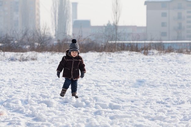 Le petit garçon marche sur le sol enneigé