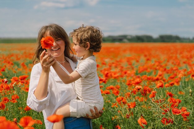 Le petit garçon et la mère jouent dans un beau champ de coquelicots rouges.