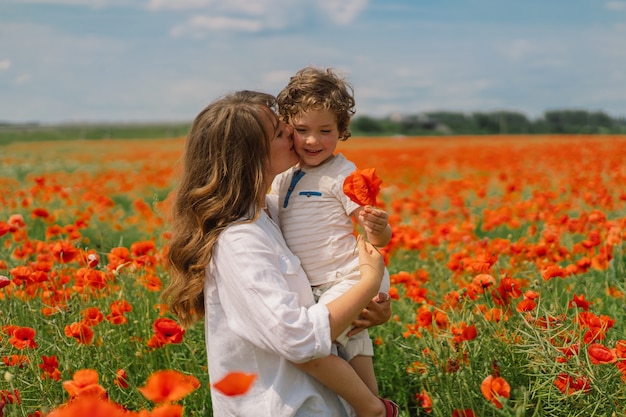 Le petit garçon et la mère jouent dans un beau champ de coquelicots rouges.