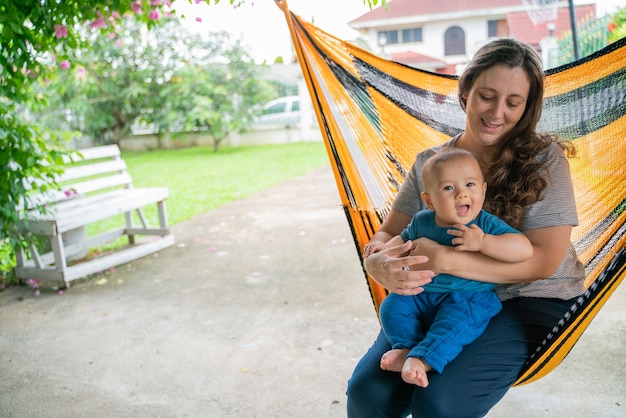 Le petit garçon et la mère sont assis au hamac, les deux sont heureux