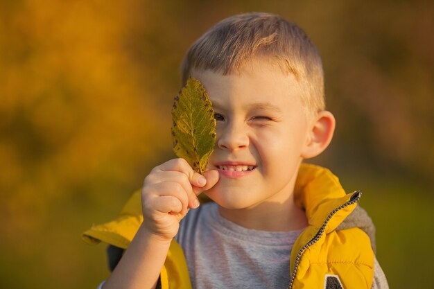 Mignon Petit Garçon De 7 Ans Joue Dans Le Parc Lumineux D'automne Portrait  D'un Enfant Heureux