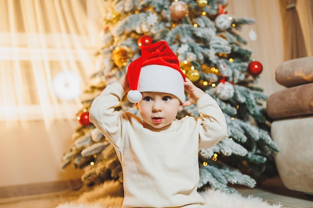 Petit garçon mignon en chapeau de père Noël avec arbre de Noël Arbre de Noël du Nouvel An pour enfants Atmosphère de Noël à la maison